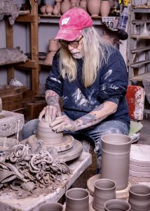 Terry Plasket throwing clay on the Potter's wheel surrounded by fresh clay