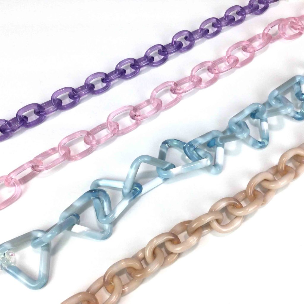 A Variety of glass chains in different sizes shapes and colors lay on a white background